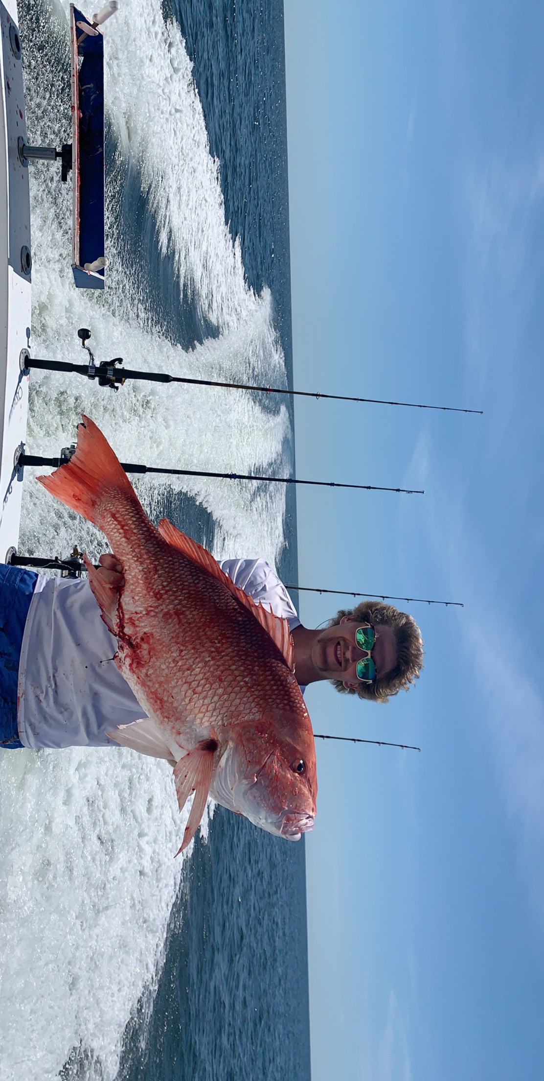man holding up red snapper on back of boat in gulf